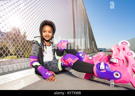 Portrait of African girl smiling, Inline Skater, assis sur le plancher du skate parc à jour ensoleillé Banque D'Images