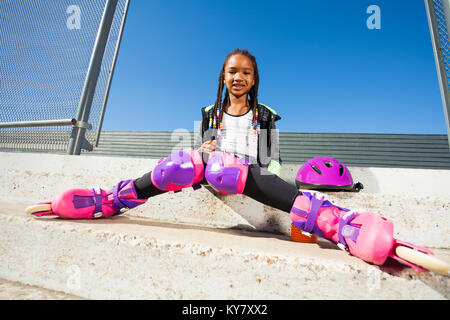 Portrait of African girl rouleau reposant sur les étapes du skate parc à jour ensoleillé Banque D'Images