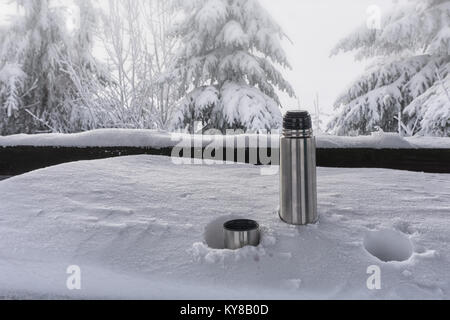 Un thermos avec du thé chaud sur une table de neige. La notion de survie, la sécurité dans les montagnes Banque D'Images