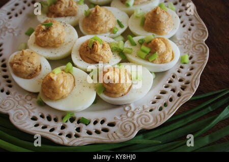 Oeufs farcis avec les foies de morue aux poireaux sur plaque blanche. Table en bois rustique. Vue d'en haut Banque D'Images