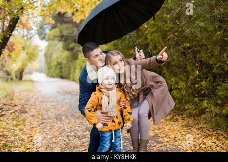 Promenade familiale dans la forêt d'automne dans le parc sous la pluie Banque D'Images