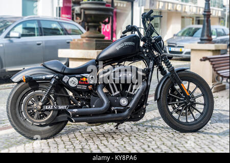 Moto Harley Davidson en noir mat en stationnement sur une rue pavée au Portugal. Banque D'Images