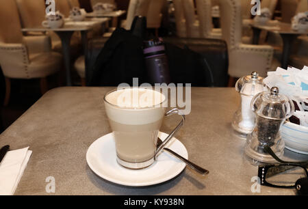 Voyage seul - tasse de café sur une table dans un aéroport avec sac à dos et une bouteille d'eau dans la chaise et chaises et tables en arrière-plan.jpg Banque D'Images