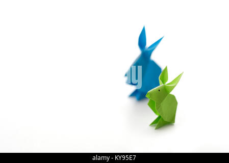 Deux petits lapins de Pâques origami colorées en papier en vert et bleu, de tailles différentes, peut-être parent et bébé debout côte à côte, prêts fo Banque D'Images