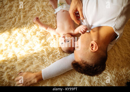 Père couché sur lit et tient son bébé Banque D'Images