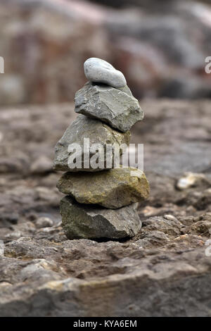 Une pile ou un tas de pierres en équilibre sur l'autre dans une œuvre artistique ou la forme sculpturale sur le bord de la mer dans l'île de Wight. Rochers empilés équilibré. Banque D'Images