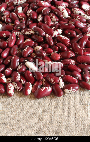 Tas de matières rouge avec des haricots rouges mouchetée blanc sur un tissu en lin Banque D'Images