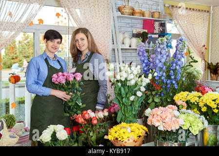 Les vendeurs de fleurs des femmes. Deux jeunes femmes travaillant dans le magasin de fleurs et de profiter de belles fleurs. Banque D'Images