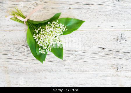 Bouquet de Lys de la vallée sur le vieux fond de bois blanc craquelé Banque D'Images