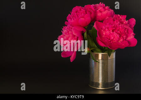 Bouquet de pivoines roses dans un vase en métal sur fond noir Banque D'Images