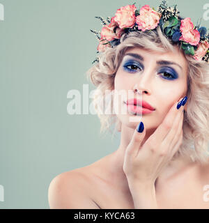 Belle Dame Fashion model avec des fleurs roses et vertes Feuilles dans ses cheveux. Cute Woman with blonde Bob Hairstyle et Main manucuré Banque D'Images