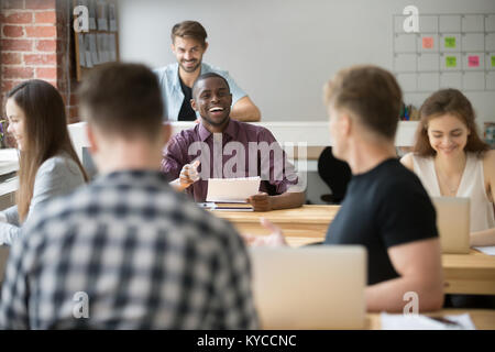 Smiling african-american couple de collègue en espace de coworking, employé attrayant noir plaisanterie drôle à dire à un collègue, friendly teamw Banque D'Images