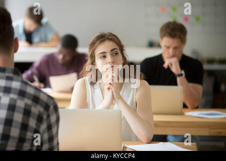 Femme sérieuse de la pensée nouvelle idée assis à un bureau avec ordinateur portable dans l'espace de co-working, distrait employé de compagnie perdue dans ses pensées, Banque D'Images