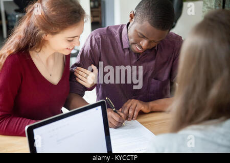 Couple multiracial de signer des documents à la réunion, young African American black man putting signature sur location vente contrat d'achat, la banque hypothécaire l Banque D'Images