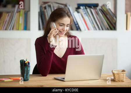 Smiling girl using laptop faire répondre à un appel à la maison Office 24, happy student parlant au téléphone à la recherche à l'écran de l'ordinateur, les jeunes pe ventes Banque D'Images