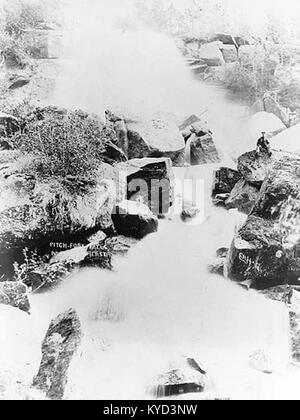 L’image d’environ 1899 intitulée « Pitchfork Falls » montre une cascade dans la nature sauvage de l’Alaska, avec de l’eau en cascade, une forêt de bois environnante et une technique photographique précoce capturant le paysage naturel du nord. Banque D'Images