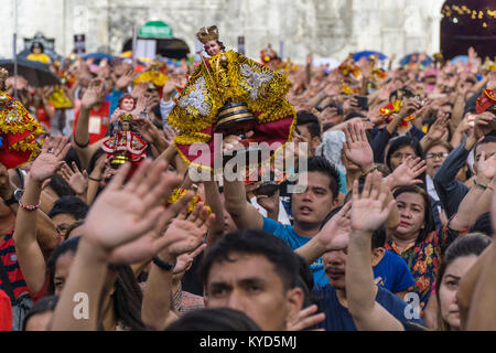 La ville de Cebu, aux Philippines. 14 janvier, 2018.les catholiques philippins lever les bras en l'air qu'ils prennent part dans le chant de l'hymne sa Gugma Batobalani.Dans le cadre de la journée 9 Sinulog festival religieux,les catholiques philippins se rassemblent pour la messe du dimanche matin, apportant avec eux des figurines Santo Nino,des répliques de l'enfant Jésus.La croyance dans cette effigie remonte à l'époque de l'explorateur Ferdinand Magellan qui a donné l'original du prince comme un don lorsqu'il a débarqué en 1521 à Cebu. Credit : gallerie2/Alamy Live News Banque D'Images