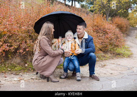 L'automne de la famille dans le parc sous la pluie parapluie Banque D'Images