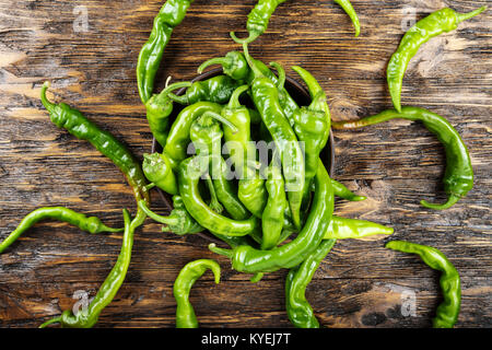 Piment vert placé dans une plaque d'argile sur une table en bois brun. Banque D'Images