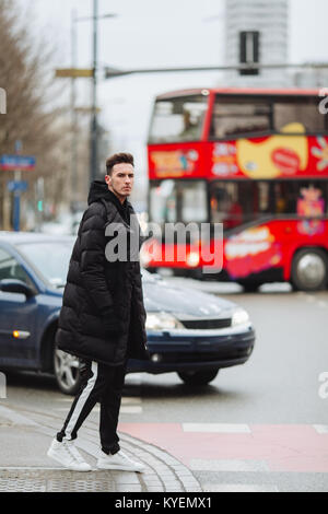 L'homme élégant wolk dans la rue. Froid d'hiver tenue. Veste avec Big White sneakers. Fond Blured street. Modèle photo Profecional. Banque D'Images