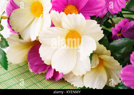 Fleurs en tissu coloré sur fond de bambou, gros plan photo. Banque D'Images