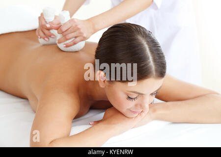 Femme dans un bain de massage avec boules de fines herbes Banque D'Images