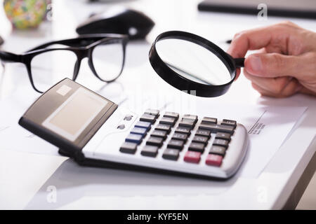Portrait Of Businessman part l'examen de la facturation avec loupe et Calculatrice dans Office Banque D'Images
