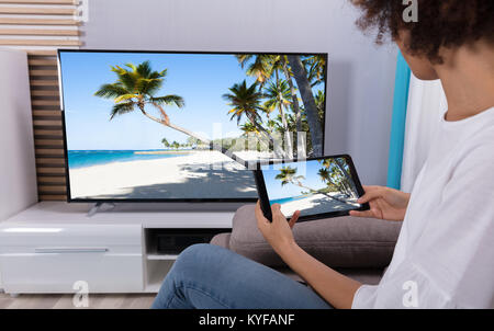 Close-up of a Woman Sitting on Sofa par chaîne de télévision connexion Wi-fi on Digital Tablet Banque D'Images