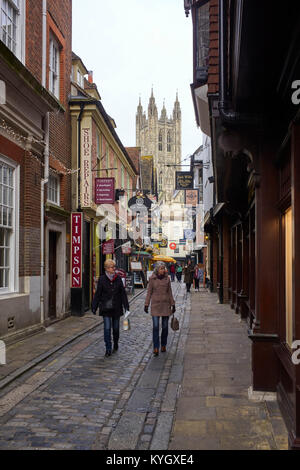 L'étroite Mercery Lane à Canterbury avec de nombreuses boutiques suspendu signes et la cathédrale en arrière-plan Banque D'Images