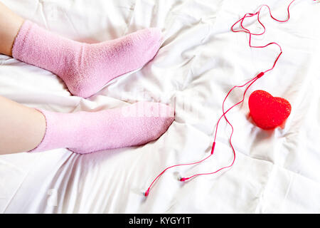 T les pieds en chaussettes. rose de la jeune fille qui assis dans le lit Banque D'Images