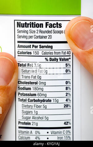 Personne doigts sur pot de protéines. Lecture du tableau de la valeur nutritive. Close-up. Banque D'Images