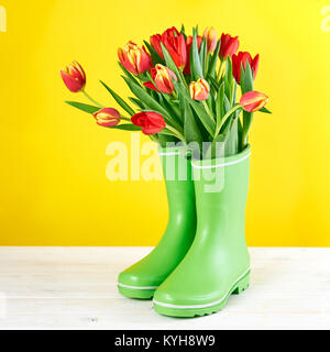 Tulipes rouges dans des bottes en caoutchouc Banque D'Images