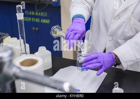 Technicien de laboratoire L'ajout d'un liquide d'un cylindre gradué au bécher Banque D'Images