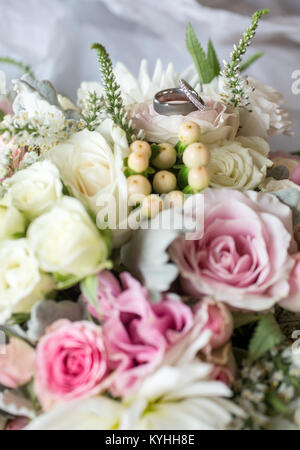 Les anneaux de mariage en appui sur le bouquet de mariée Banque D'Images