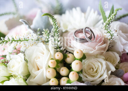 Les anneaux de mariage en appui sur le bouquet de mariée Banque D'Images