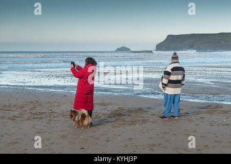 Plage de Polzeath - un couple de personnes et leur chien sur la plage de Polzeath sur la côte nord des Cornouailles. Banque D'Images