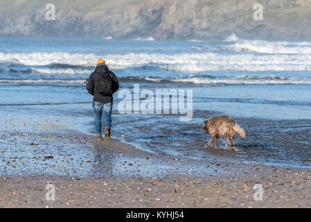 Polzeath - une marchette et son chien sur la plage de Polzeath sur la côte nord des Cornouailles. Banque D'Images