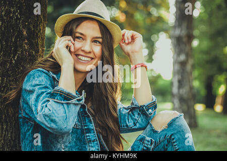 Pretty girl talking on mobile phone. Belle fille occasionnels using smartphone smiling happy en extérieur dans un parc. Portrait d'une jeune fille moderne, tendance wi Banque D'Images