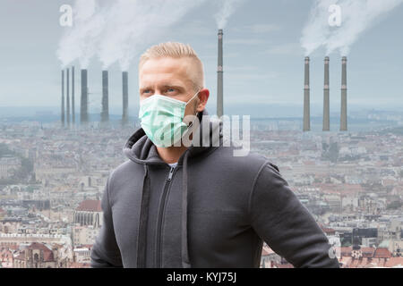 Portrait d'un homme portant un masque de bouche contre la fumée des cheminées d'émission Banque D'Images