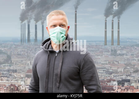 Portrait d'un homme portant un masque de bouche contre la fumée des cheminées d'émission Banque D'Images