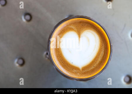 Vue de dessus du café cortado dans un verre avec de la mousse en forme de coeur Banque D'Images