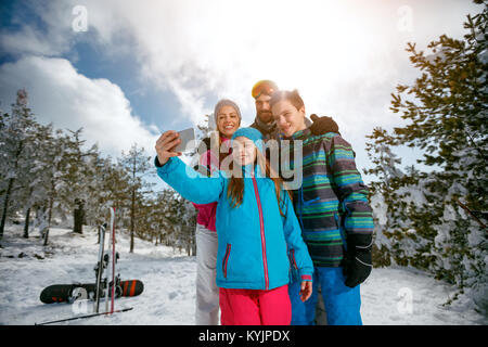 Famille heureuse rire et sur mobile avec selfies hiver ski locations Banque D'Images