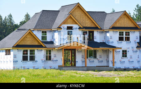 Grande maison en construction dans la belle campagne du nord-ouest du Pacifique de Bellingham, Washington, USA. Un travailleur de la construction sur le toit de terrasse. Banque D'Images