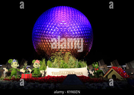 Disney's Epcot Center sphere éclairée la nuit pendant la saison des Fêtes avec Mickey, Minnie et Pluto herbe personnages sculptures en face. Banque D'Images