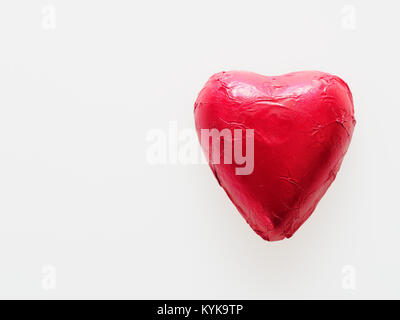 Chocolat en forme de coeur rouge enveloppé de papier aluminium isolé sur fond blanc utilisation dans la St Valentin ou problème lié à l'amour Banque D'Images