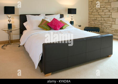 Couverts contemporains en cuir lit double avec tables et lampes de chevet Banque D'Images