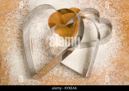 Un ensemble de trois en forme d'coeur emporte-pièce sur un arrière-plan saupoudré de farine Banque D'Images
