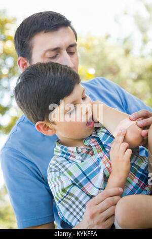 Père aimant met un bandage sur le coude de son jeune fils dans le parc. Banque D'Images