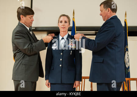 Le colonel Kathryn Pfeifer's mari (à gauche) et l'adjudant-général du Kentucky, le Major-général Edward Tonini, broche insigne de grade du colonel de son uniforme au cours d'une cérémonie à la promotion de la base de la Garde nationale aérienne du Kentucky à Louisville, Ky., 17 août 2013. Pfeifer, directeur de cabinet de l'Administration centrale, Kentucky Air National Guard, est la première ligne féminine commissariat pour atteindre le grade de colonel dans la garde de l'air du Kentucky. (U.S. Photo de la Garde nationale aérienne Aviateur Senior Vicky Spesard) Banque D'Images