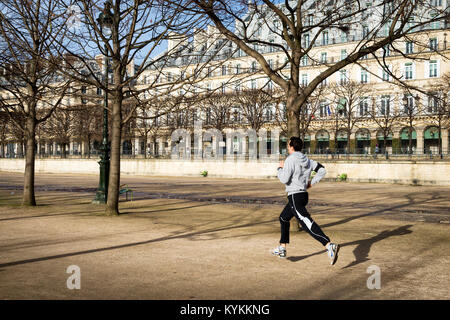 PARIS-Jan 5, 2014 : un jogger s'exécute dans le jardin des Tuileries, parc avec grands bâtiments en arrière-plan. Ses pieds ne touchent plus le sol. Ciel bleu sur un wint Banque D'Images